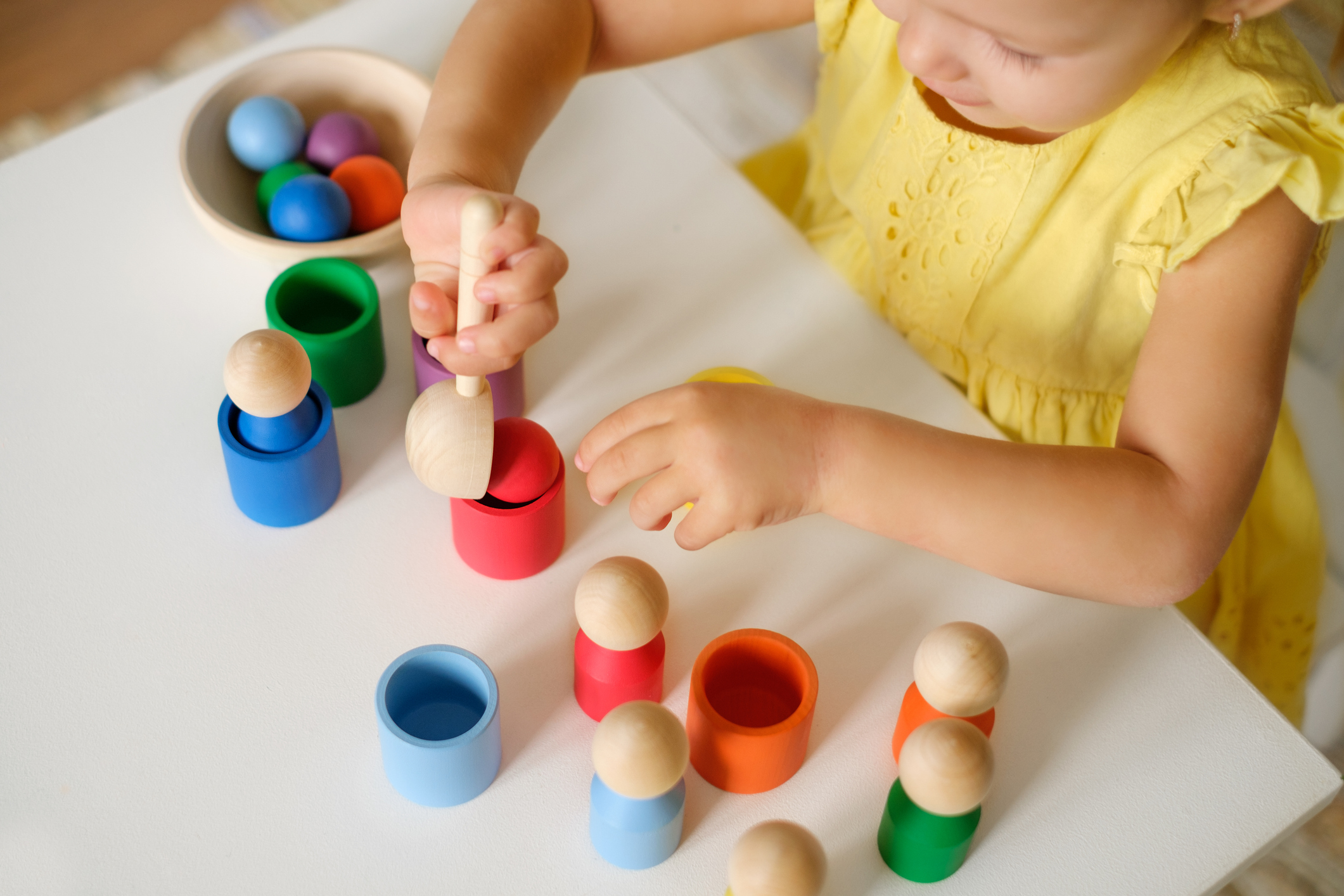 Toddler plays with different figures at the table, sorting them by color