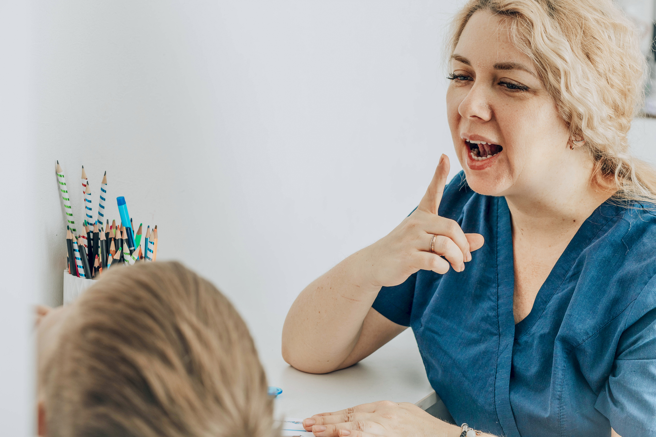 woman speech therapist teaching young boy in a classroom setting, engaging with a lively expression, concept of early childhood education, special education