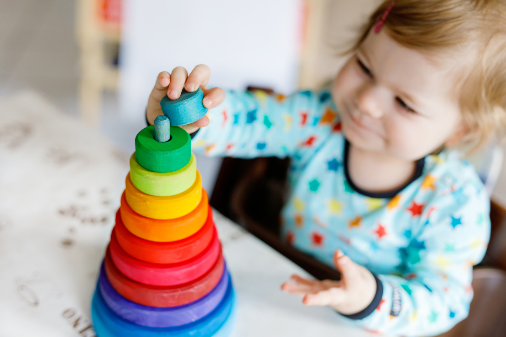 Adorable cute beautiful little baby girl playing with educational wooden rainbow toy pyramid
