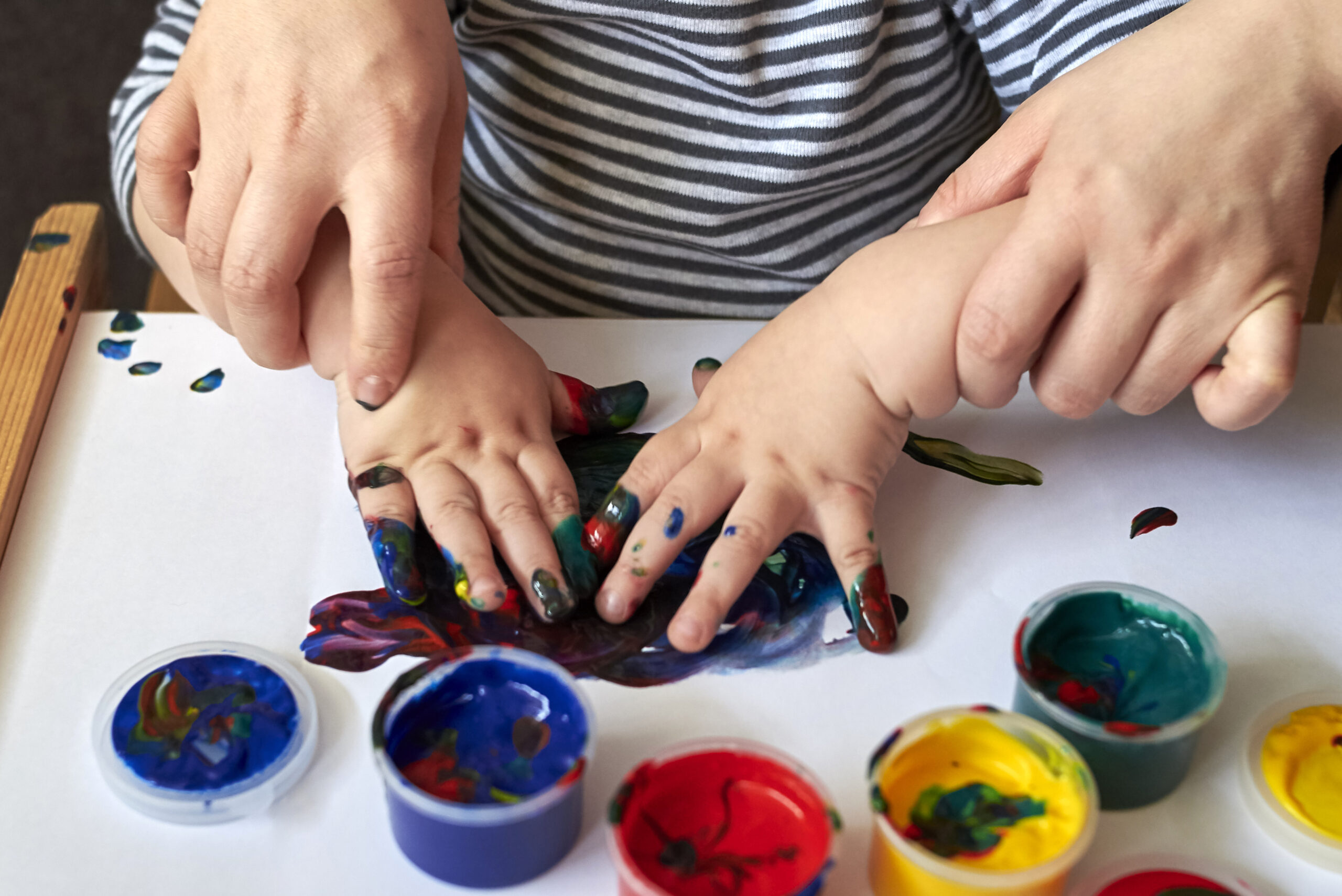 Mom teaches a child to draw with finger paints.